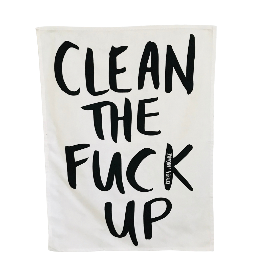 A white kitchen towel with the text 'CLEAN THE FUCK UP' written in black.