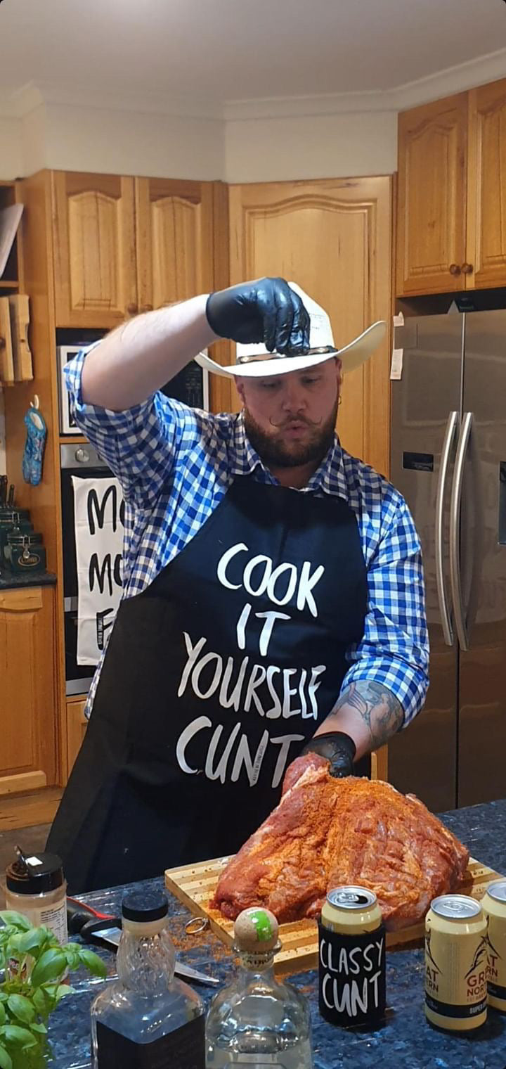 Man cooking with Cook It Yourself Cunt apron